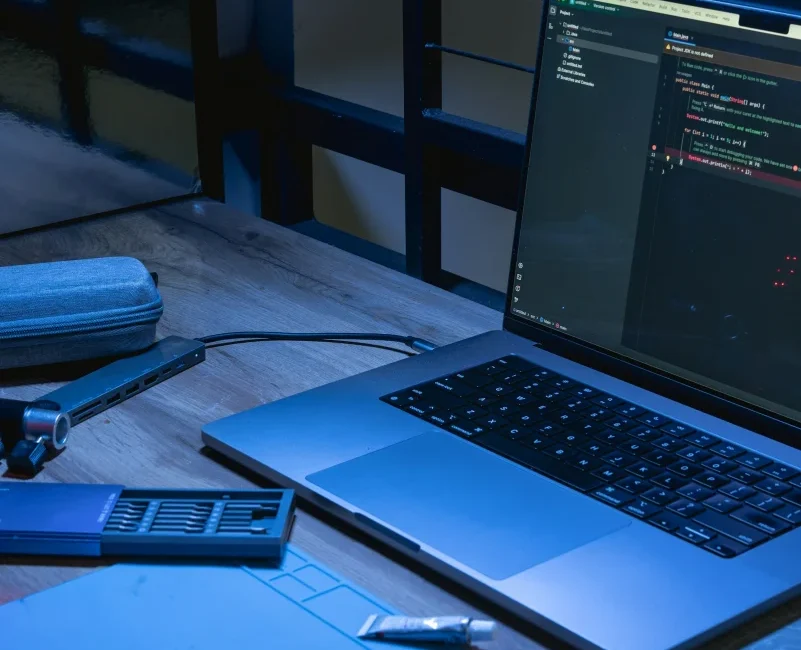 Portátil con código y un teléfono sobre una mesa de madera